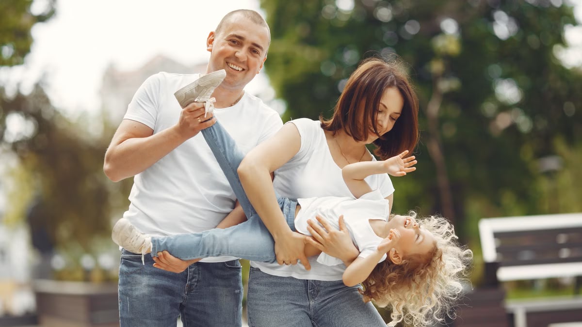 Happy family enjoying playful moments outside on a sunny day.